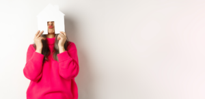 real-estate-funny-asian-middleaged-woman-hiding-face-paper-house-model-showing-puckered-l Medium
